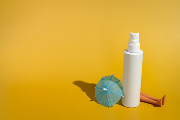 Blank white spray bottle with umbrella and doll legs in direct sunlight - obrazy, fototapety, plakaty