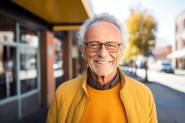 Portrait of a grinning man in his 70s wearing a chic cardigan isolated in solid color backdrop