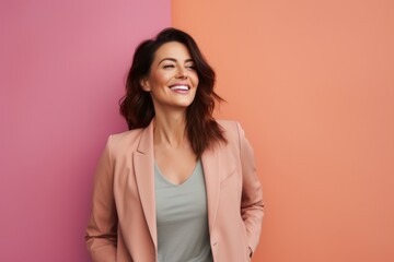 Obraz premium Portrait of a blissful woman in her 40s dressed in a stylish blazer while standing against solid pastel color wall