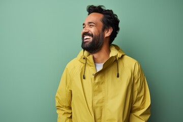 Portrait of a happy man in his 40s sporting a waterproof rain jacket isolated in solid pastel color wall