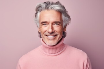 Portrait of a glad man in his 50s showing off a thermal merino wool top in front of solid pastel...