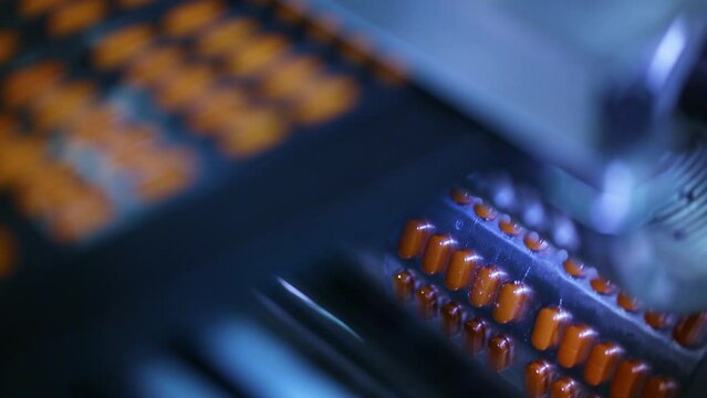 Medicinal tablet packing machine close up. machine packaging tablets in blister, alu alu packing. equipment sealing tablets in packets. automatic sealing machine in a pharmaceutical manufacturing.