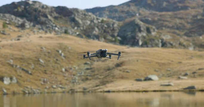 Flying DJI Air professional drone flying suspended in static mode over mountain lake