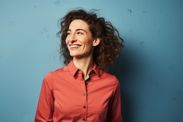 Portrait of a blissful woman in her 30s sporting a technical climbing shirt over blank studio backdrop