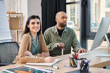A man with myasthenia gravis and woman engrossed in work, sitting at a desk in front of a computer...