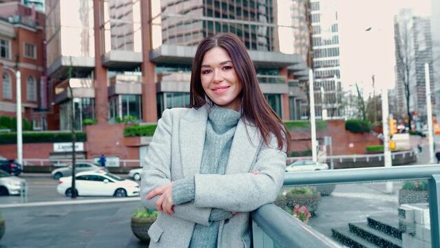Young smiling professional business woman, happy confident 30 years old lady standing outdoors on big city street business district, looking at camera, crossing arms, portrait.