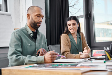 disabled man and a woman sit at a desk in an office, engrossed in their work as they collaborate on a project.