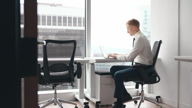 Serious business man executive, male investor wearing shirt and tie typing on computer technology sitting at workplace. Busy professional businessman manager using laptop working in office.