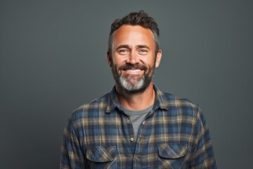 Portrait of a satisfied man in his 40s wearing a comfy flannel shirt isolated on blank studio backdrop - obrazy, fototapety, plakaty