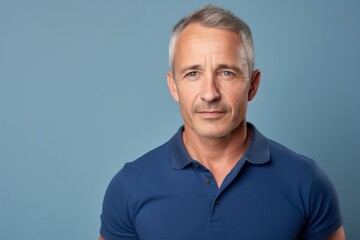 Portrait of a merry man in his 50s wearing a sporty polo shirt on light wood minimalistic setup
