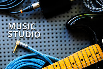 Electric guitar, Instuments and cable on a gray background with the word Music Studio. Music concept