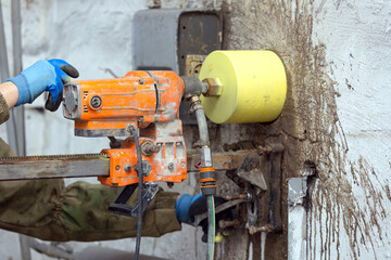 Worker using an electric drill to make a hole in a concrete wall, closeup - 789145582