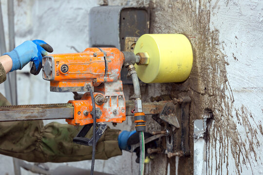 Worker using an electric drill to make a hole in a concrete wall, closeup