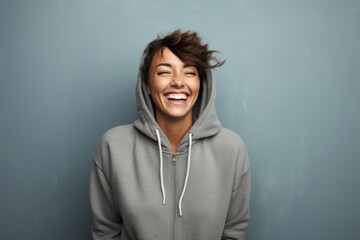 Portrait of a happy woman in her 30s wearing a zip-up fleece hoodie in plain cyclorama studio wall - obrazy, fototapety, plakaty