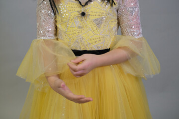 Close-up on ornate beadwork and sheer sleeves of a child's yellow gown, highlighting the elegance of special occasion attire.