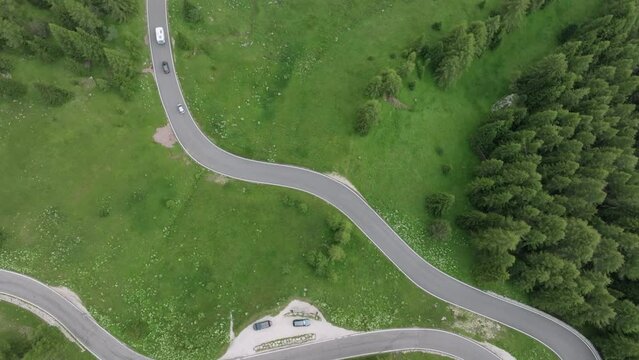 An aerial tilt up drone shot captures multiple cars winding along the roads near Selva Pass in the Dolomite Mountains, Trentino, South Tyrol, Italy. LuPa Creative.