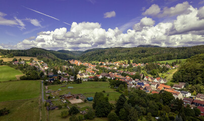 Aer ial view of a German village surrounded by meadows, farmland and forest. Germany.