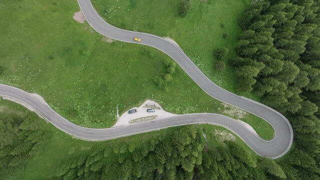 An aerial view shows two cars traversing the winding roads near Selva Pass in the Dolomite Mountains, Trentino, South Tyrol, Italy. LuPa Creative.