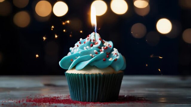 A blue cupcake with a lit candle on top