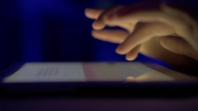 Girl Typing on Touch Screen Digital Tablet at Night. Hands of Person Typing Article Text or Document on Mobile Computer Close Up. Human Hands Typing Text Message Email on Tablet Touch Screen Keyboard.