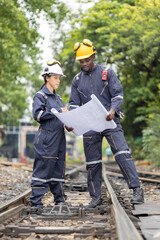 Railway Workers Discussing Plans on Railroad Track