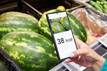 Checking calories on watermelon in store with smartphone