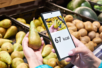 Checking calories on pear fruit in store with smartphone