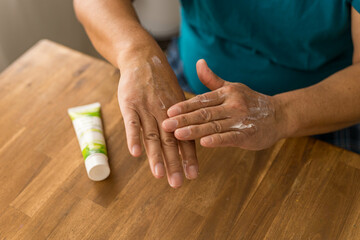 skin care, hands smeared with cream on dark background