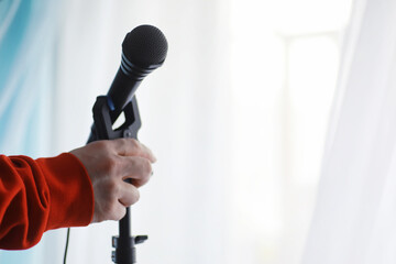 Stand with a microphone. Man holds hands a microphone on a tripod. Performance of the artist with a...