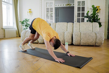 A focused individual practices a yoga pose on a mat, displaying discipline and balance in a serene...