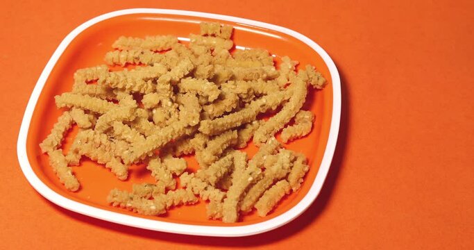 Indian popular snack butter murukku serving on plate against orange background. India and prepared during festivals