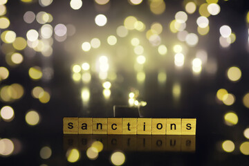 word sanctions spelled in letters on table made of wooden block letters with dramatic lighting and smoke - obrazy, fototapety, plakaty