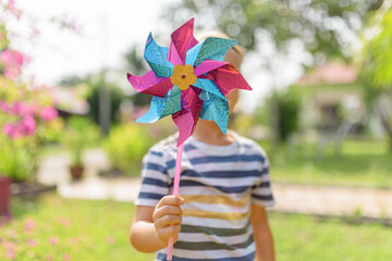Little boy is playing with pinwheel in a garden - 789201115
