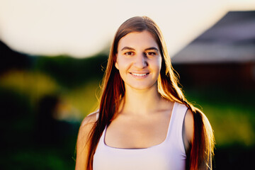 Outdoors portrait of young European woman in light of setting sun in rural area, close-up.
