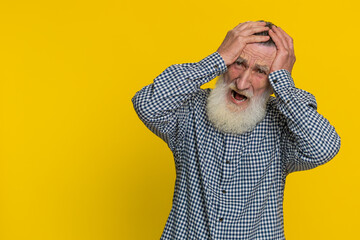 Irritated angry senior old aged man screams from stress tension problems feels horror hopelessness fear surprise shock expresses rage nervous, quarrel. Mature bearded grandfather on yellow background