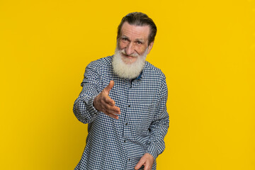 Friendly senior old man outstretching hand to camera offering handshake greeting with kind smile...