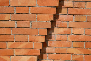 Fototapeta premium exposed brick wall, construction detail of a wall with decorative elements given by the simple exchange of textures, joint between exposed bricks on the facade of a prestigious building.