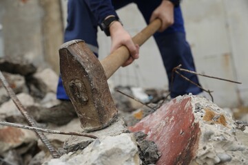 Man breaking stones with sledgehammer outdoors, selective focus