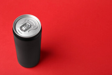 Energy drink in can on red background, space for text
