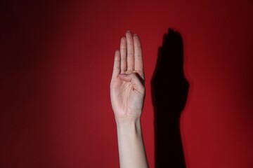 Woman showing open palm on red background, closeup