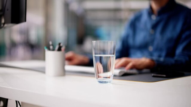 Glass Of Water On Desk And Man In Background