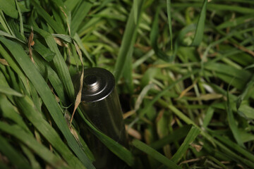A spent finger battery on withering grass. Close-up.