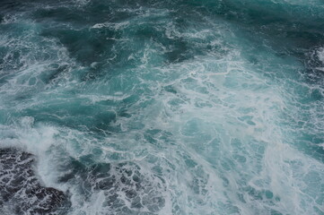 The white crashing waves and the emerald sea