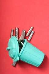 Used finger batteries in a miniature trash can. Pink background. Close-up. Field for text.