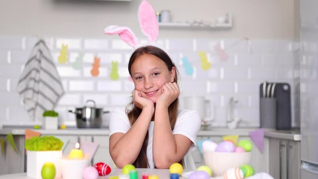 a teenage girl in the interior of a home kitchen decorated for Easter decorates Easter eggs