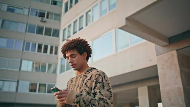 Man recording audio notification on smartphone at residential complex closeup.