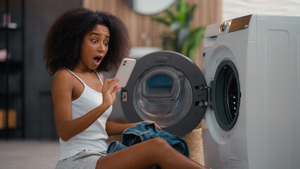 African American woman housewife sad upset shocked biracial ethnic girl pull out of washing machine...
