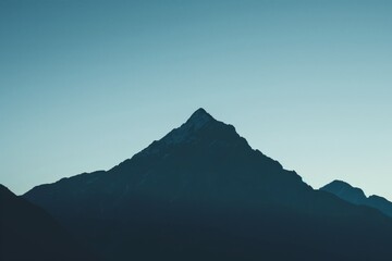 Minimalist photo capturing the silhouette of a mountain peak against a twilight sky