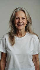 Studio shot of a cheerful elderly woman with long gray hair with no makeup and wearing white t-shirt - obrazy, fototapety, plakaty