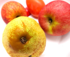 pear with apple and tomato in the background. set of fruits. Green fruit with red berries. food with selective focus.